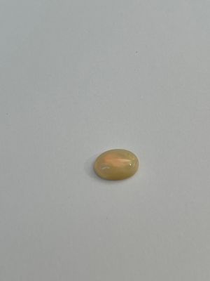 an oval yellow oplite stone on a white surface