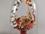 un dôme en verre contenant une figurine représentant une femme tenant un panier de fleurs
