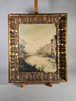 une peinture à l'huile représentant un paysage fluvial, dans un cadre doré, posée sur un chevalet en bois