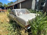 une vieille voiture abandonnée dans les herbes devant une maison