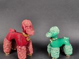 une paire de figurines de caniches rouges et verts posées sur un socle noir