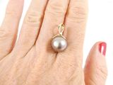 a woman ' s hand holding a ring with a pearl on it
