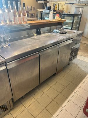 stainless steel counter with wine glasses on top of it in a restaurant