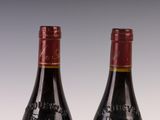 two bottles of red wine sitting next to each other on a table