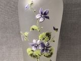 un vase en verre sur lequel sont peintes des fleurs violettes