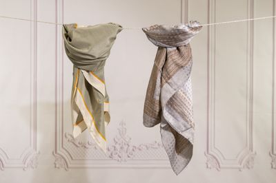 two towels hanging on a clothes line with a wall in the background