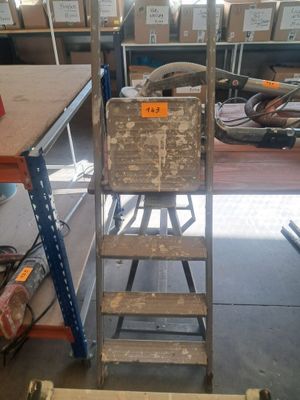une échelle sur laquelle est posée une boîte, au milieu d'une pièce