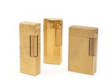 three gold colored lighters sitting next to each other on a white surface