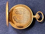 an image of a gold pocket watch on a blue surface