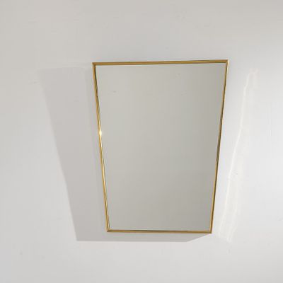 un miroir à cadre doré accroché au mur d'une pièce blanche