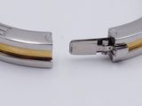 two pieces of silver and gold metal bracelets on a white surface