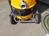 a yellow dust collector with a hose on the ground