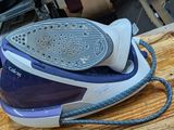 a blue and white steam iron sitting on a wooden table