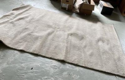 un grand tapis posé à même le sol, à côté d'une pile de cartons