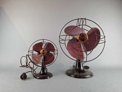 two small metal fans sitting side by side on a white surface
