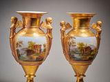 deux vases en or ornés de peintures, posés sur une table