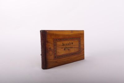 un vieux livre à la couverture en bois posé sur une surface blanche