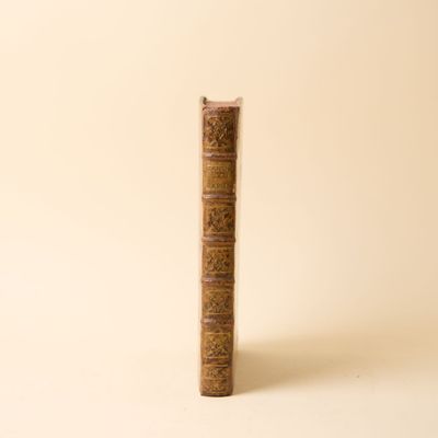 un vieux livre posé sur une table à côté d'un mur blanc