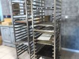 several trays of food sit on a metal rack in a kitchen