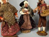 three figurines of people dressed in traditional clothing and hats