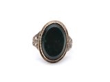 a close up of a ring with a green stone in it