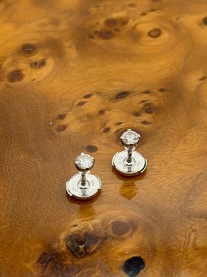 une paire de boucles d'oreilles en argent posée sur une table en bois de burlock
