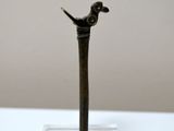 a small bronze figurine of a bird on top of a glass stand