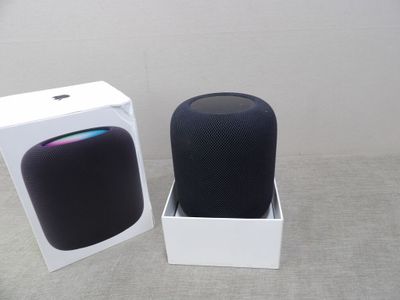 une enceinte HomePod d'Apple dans une boîte, à côté d'une autre boîte dont le couvercle est ouvert
