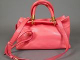 a pink handbag with gold handles and a strap