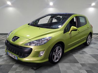 Une voiture verte est garée dans une pièce au sol à carreaux.