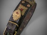 a close up of a black leather bracelet with gold and red accents
