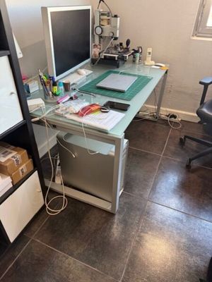 un bureau en verre sur lequel est posé un ordinateur