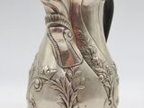 an antique silver coffee pot on a stand on a white background