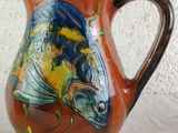 a brown pitcher with a fish painted on it