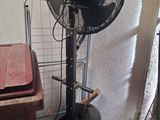 a fan sitting next to a trash can in a room