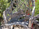 a wooden bench made out of branches in the middle of a garden