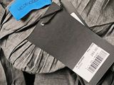 a tag on a shirt that is sitting on a pile of clothes