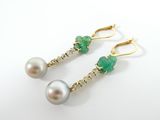 a pair of pearl and emerald earrings on a white background
