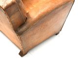 a brown leather chair that is sitting on a white surface