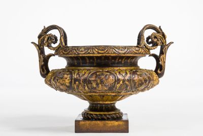 a bronze vase on a stand on a white background
