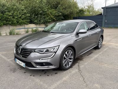 La voiture grise est garée sur le parking, à côté d'un immeuble.