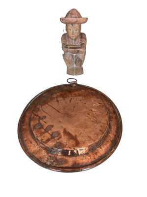 une petite statue représentant un homme debout sur une casserole en métal