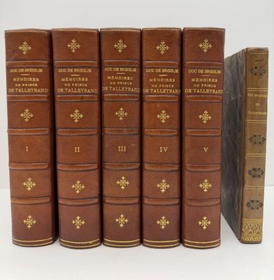 six vieux livres sont alignés sur une surface blanche