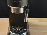 a coffee maker sitting on a wooden table next to a cup of coffee