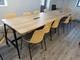 a long table with yellow chairs and a laptop on it