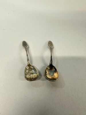 pair of silver spoons sitting on top of a white surface