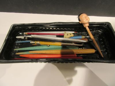 de nombreux stylos et crayons dans un récipient noir posé sur une table