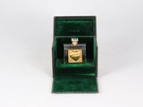 a small green box with a bottle of perfume inside of it