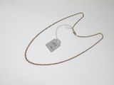 une photo d'un collier muni d'une étiquette, posé sur une surface blanche