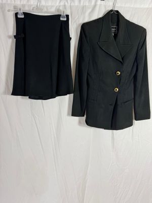 un tailleur noir et une jupe sont suspendus à un cintre
